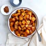 cinnamon roasted butternut squash in a serving platter on a counter next to bowls with seasonings