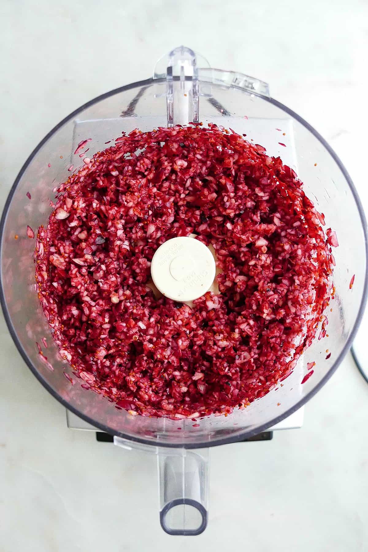chopped cranberries in an open bowl of a food processor on a counter