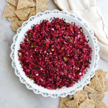 cranberry jalapeno dip in a serving dish next to triscuit crackers on a counter