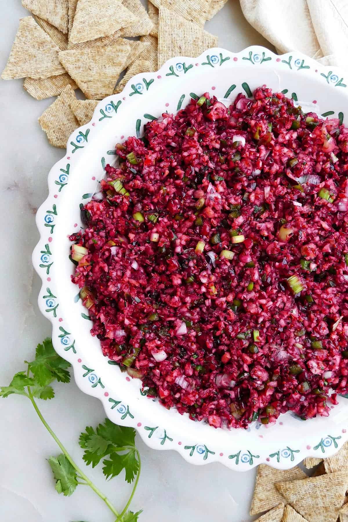 close image of cranberry jalapeno dip with fresh cilantro next to crackers