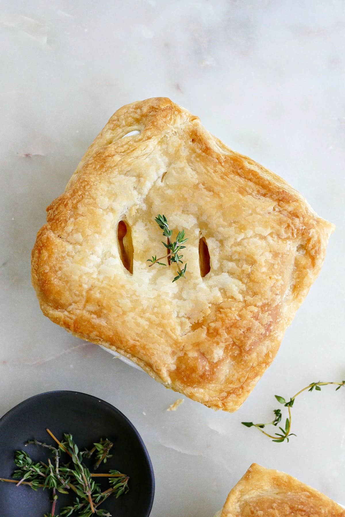 mini vegetarian pot pie topped with thyme sprigs on a counter
