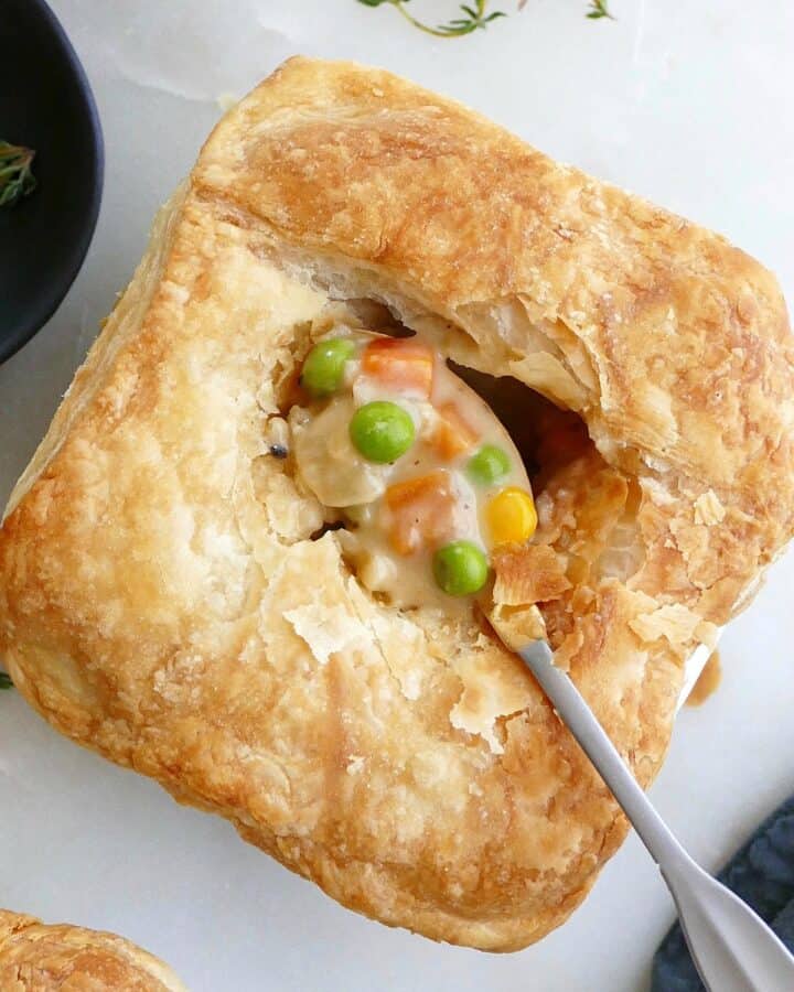 square image of mini vegetarian pot pie with a small spoon with filling in the center