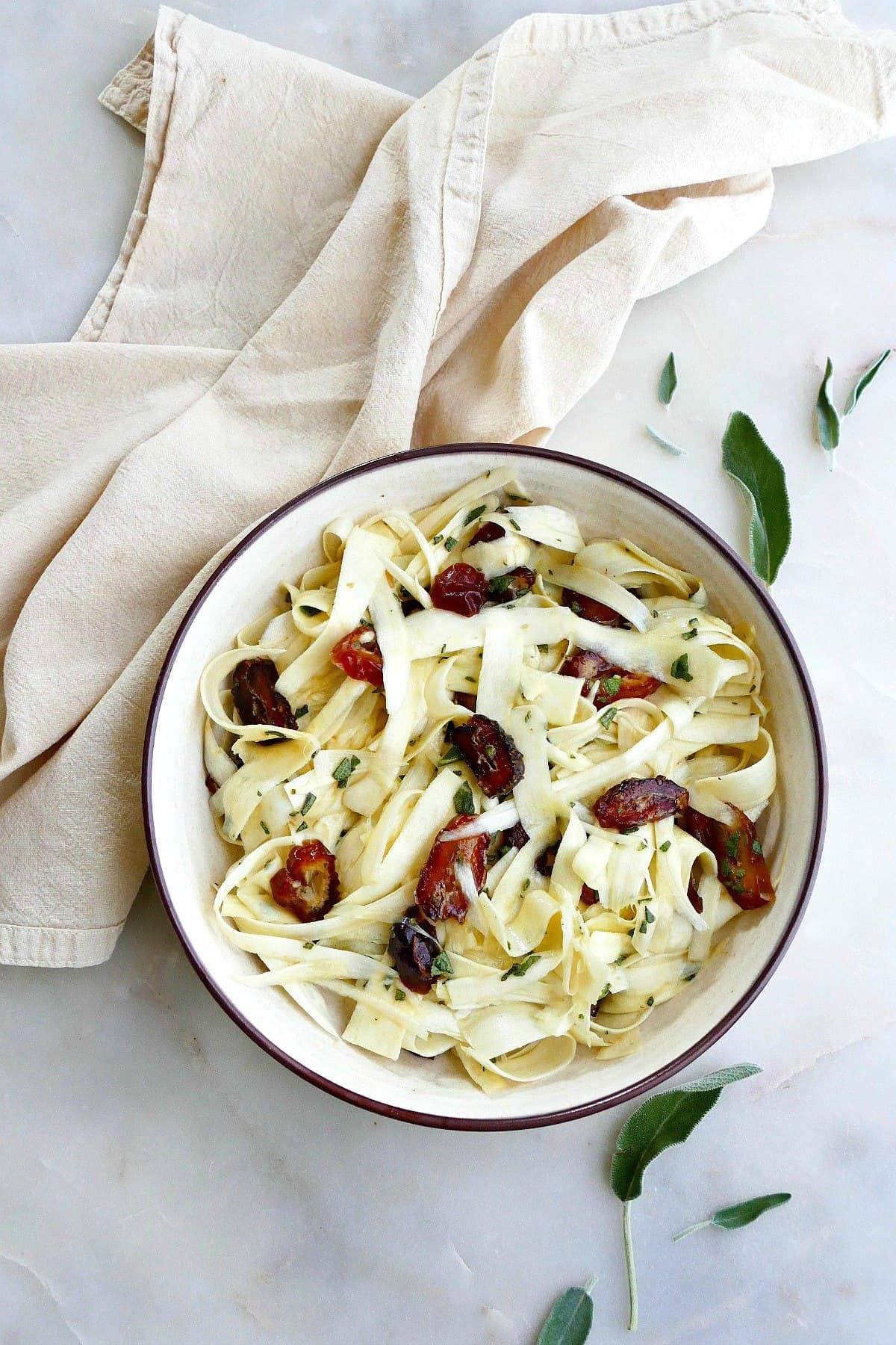 raw parsnip salad with dates and sage in a serving bowl on a counter