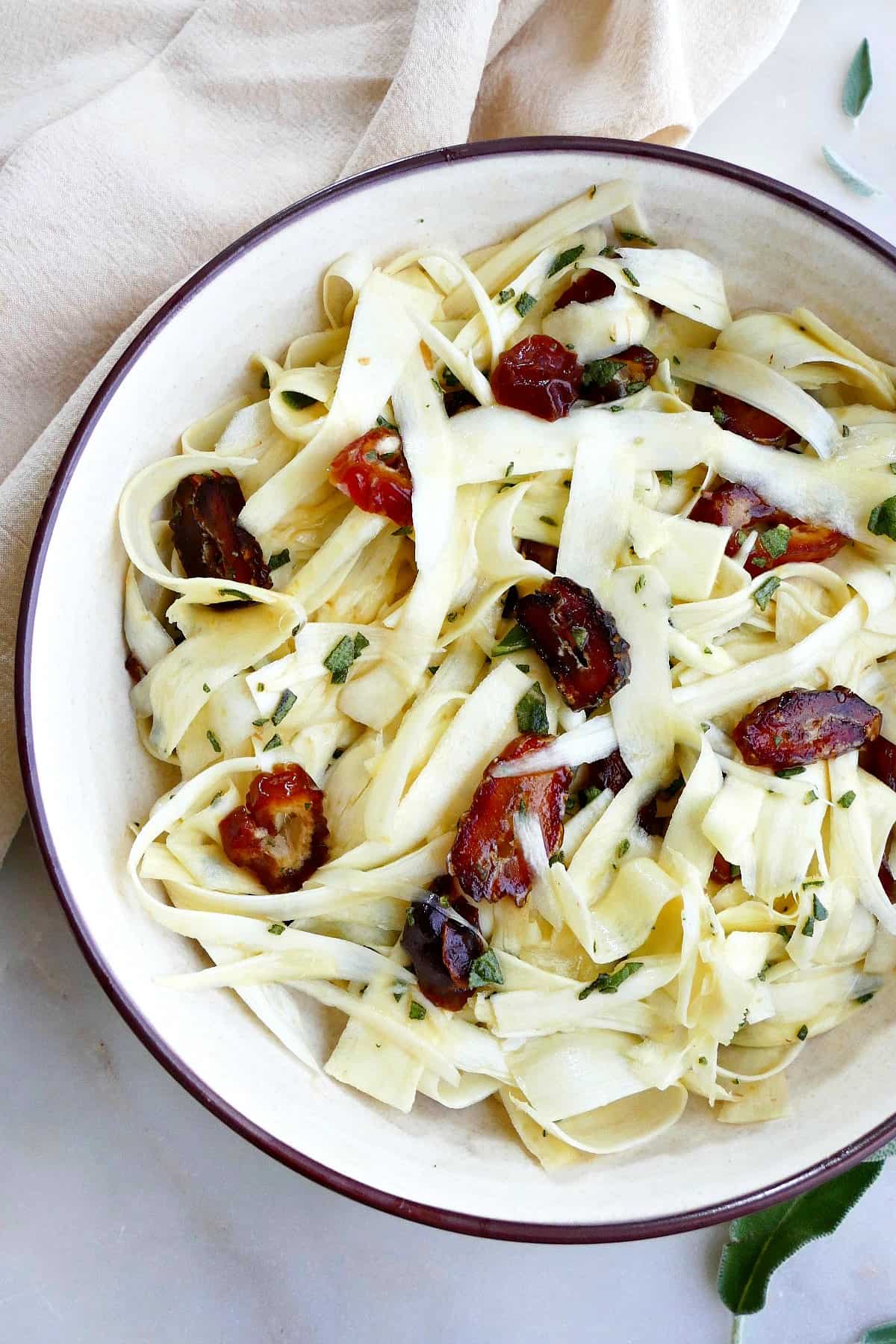 close-up image of raw parsnip salad with dates and sage in a serving bowl