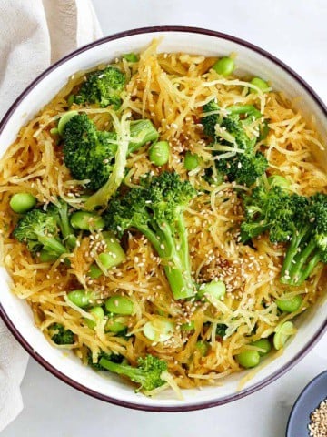 square image of spaghetti squash stir fry with edamame and broccoli in a serving bowl on a counter