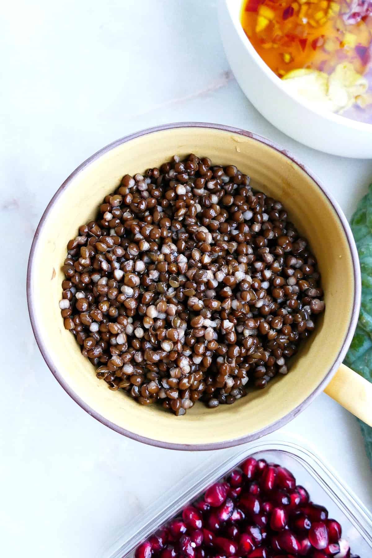 black lentils in a yellow coffee mug on a counter next to ingredients