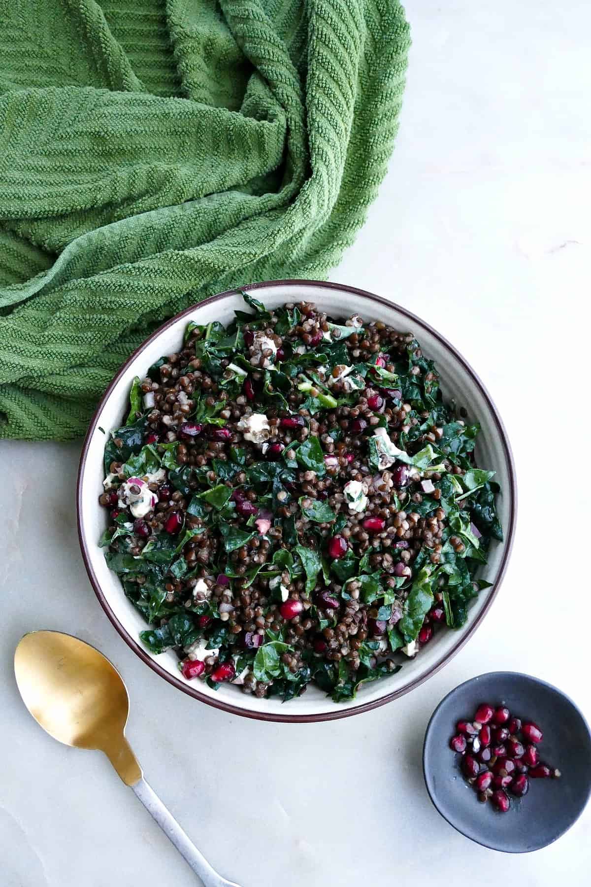 black lentil and kale salad in a serving bowl next to a napkin and spoon