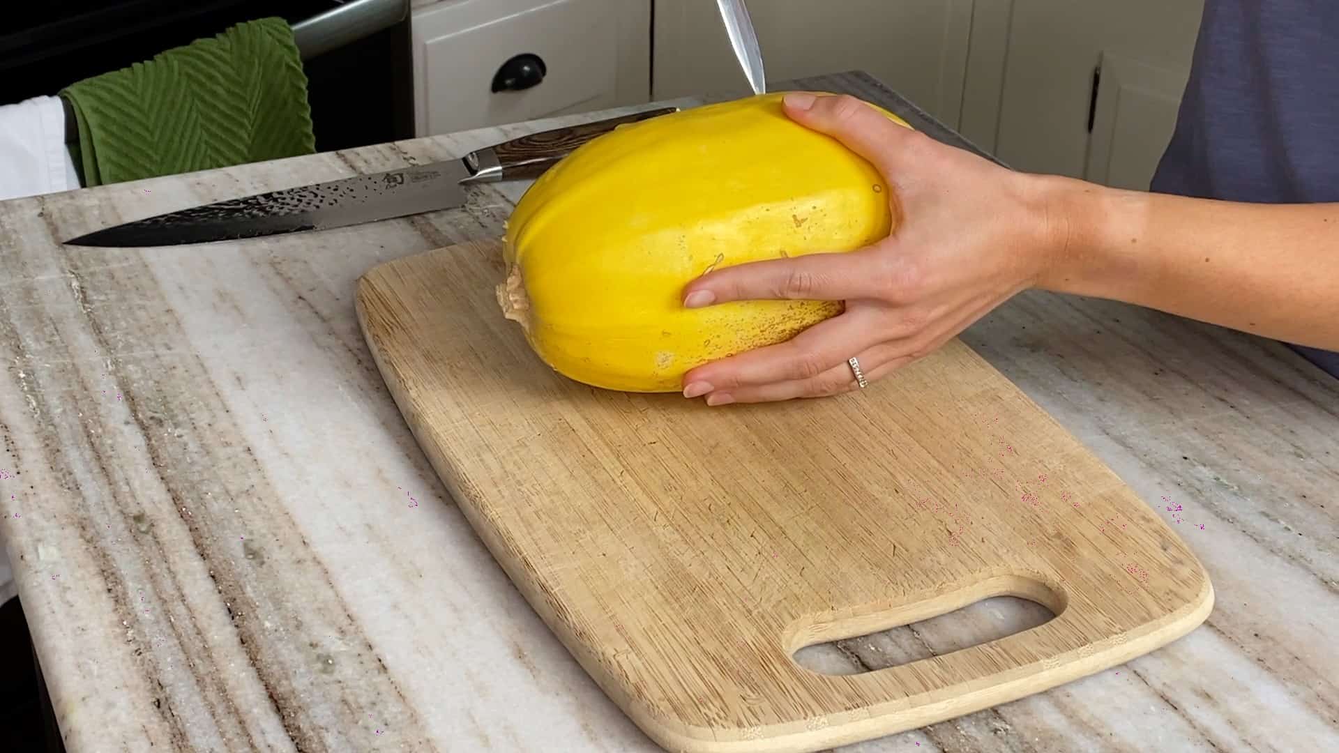 woman holding a spaghetti squash and making slits with a knife