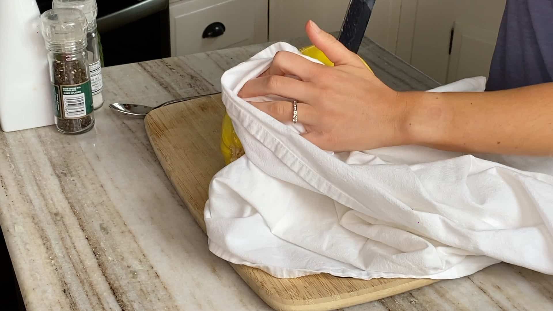 woman holding a spaghetti squash with a dish towel and cutting it