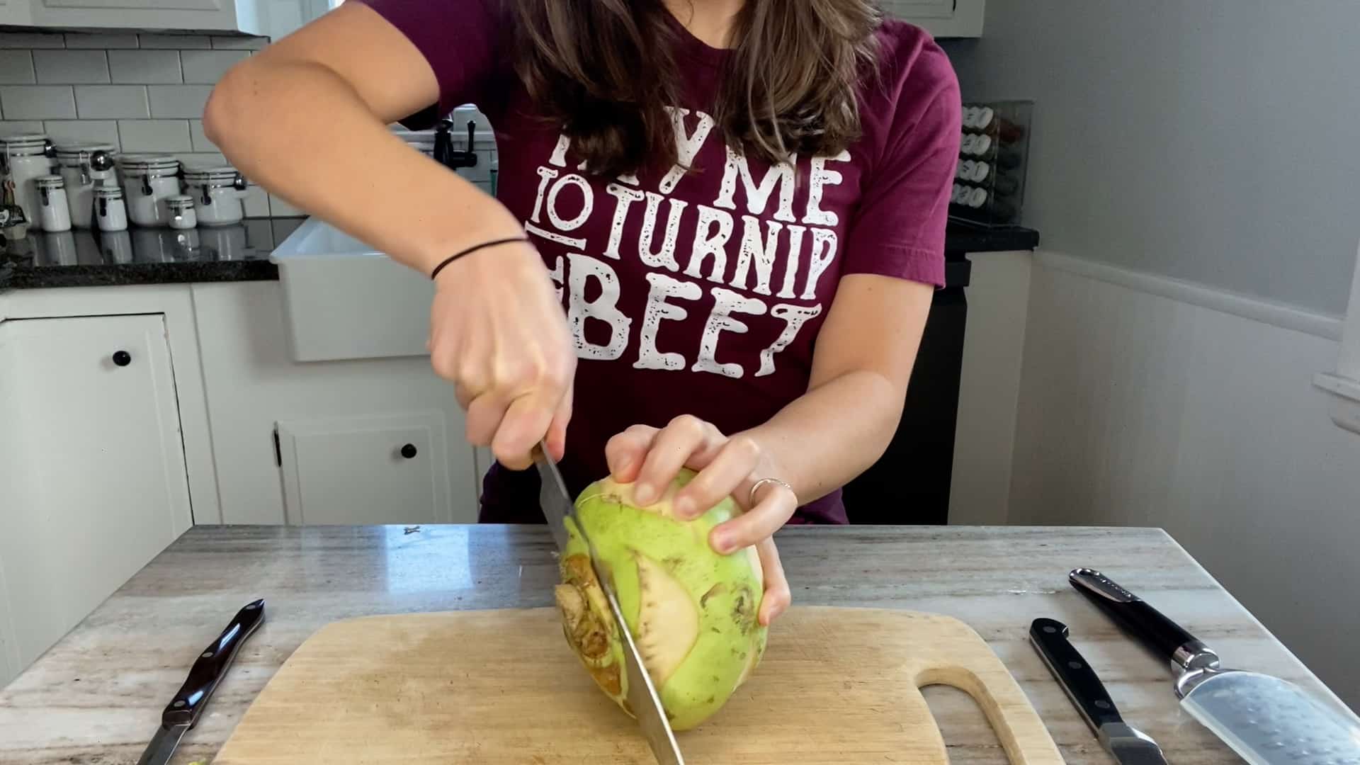 photo of woman cutting the ends off of a green kohlrabi
