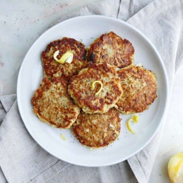 six kohlrabi fritters topped with lemon zest on a serving platter