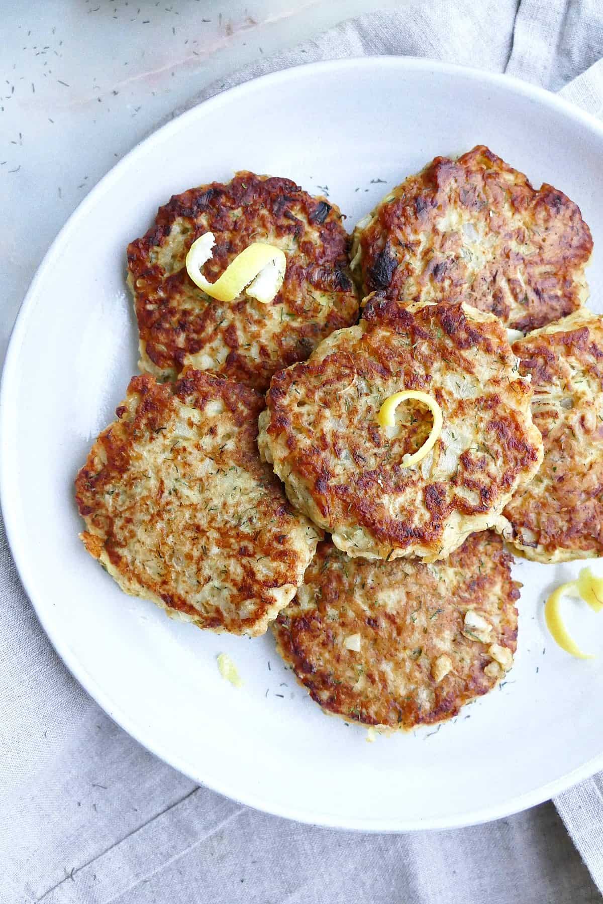 close-up image of kohlrabi fritters with lemon zest on a serving plate