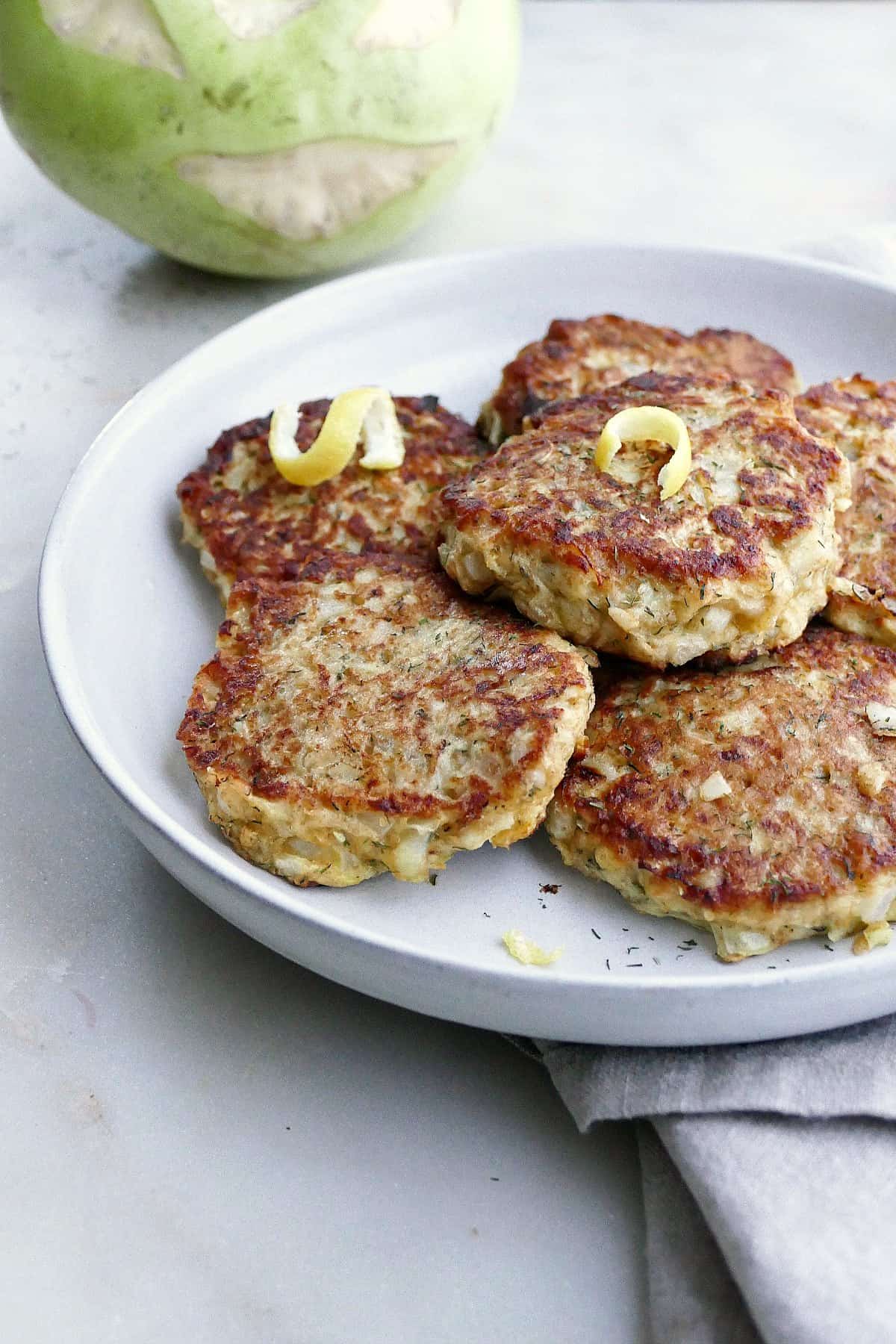 side image of kohlrabi fritters on a platter in front of a raw kohlrabi