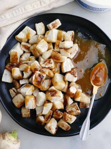 square image of roasted turnips with miso butter on a black serving plate