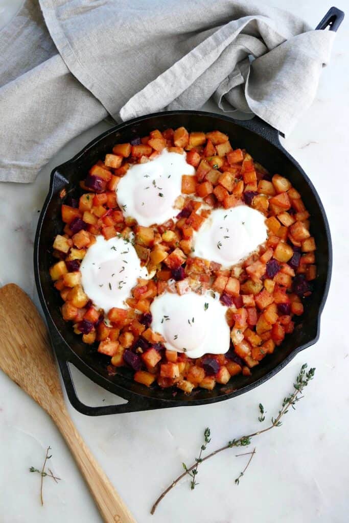 root vegetable has in a skillet topped with four eggs on a counter