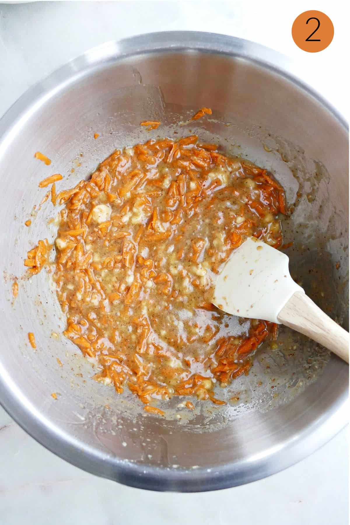 batter for muffins with shredded carrots in a mixing bowl with a spatula