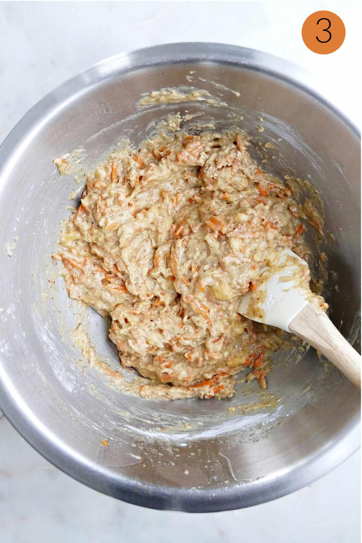 batter for banana carrot muffins mixed with dry ingredients in a mixing bowl