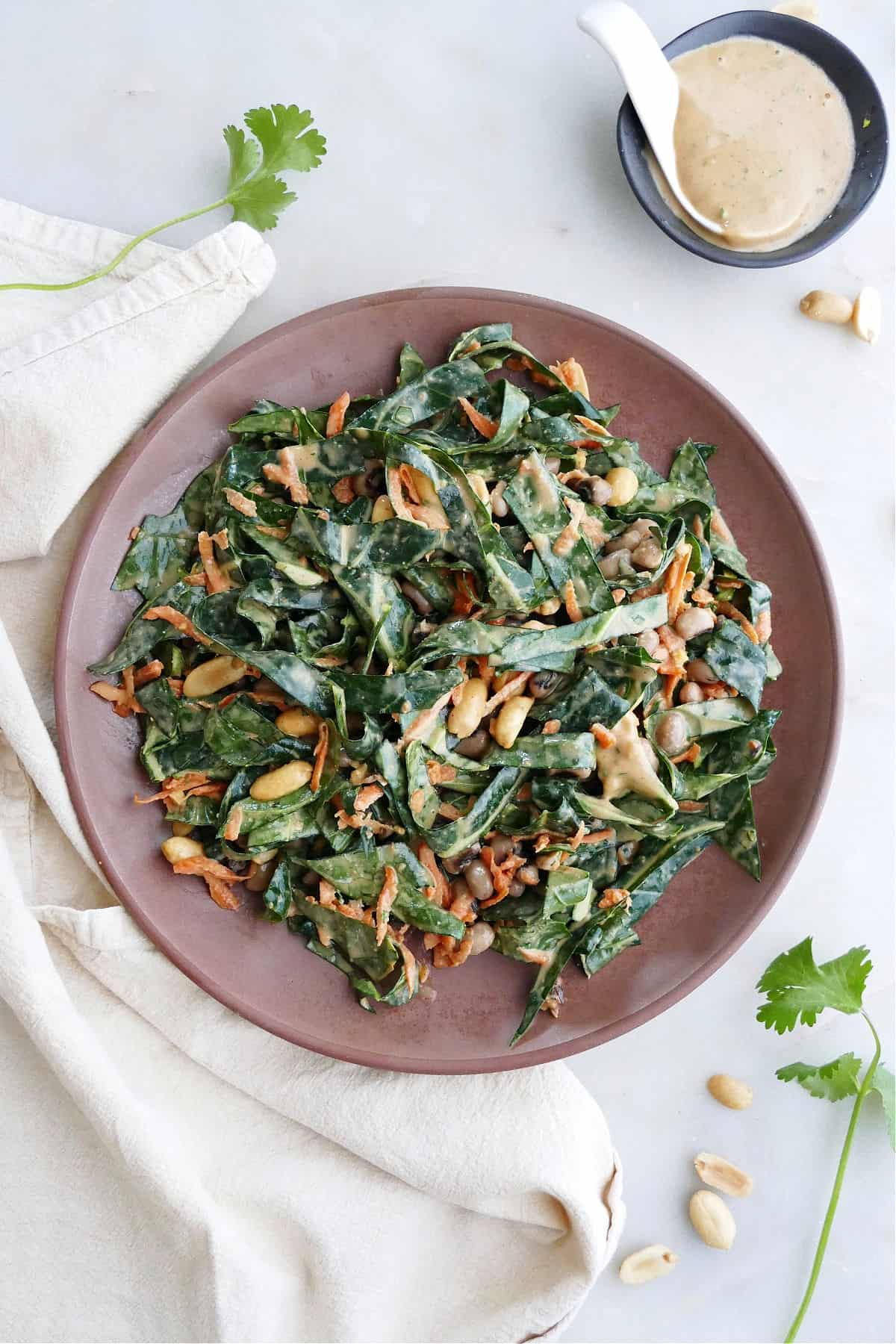 collard greens salad with peanut dressing on a brown serving dish on a counter