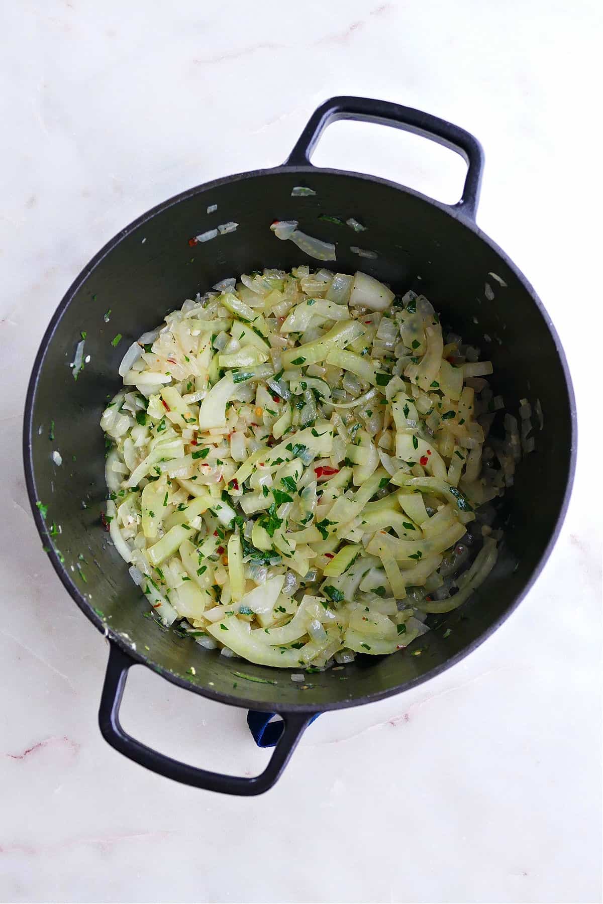 cooked fennel, onion, garlic, and parsley in a black pot on a counter