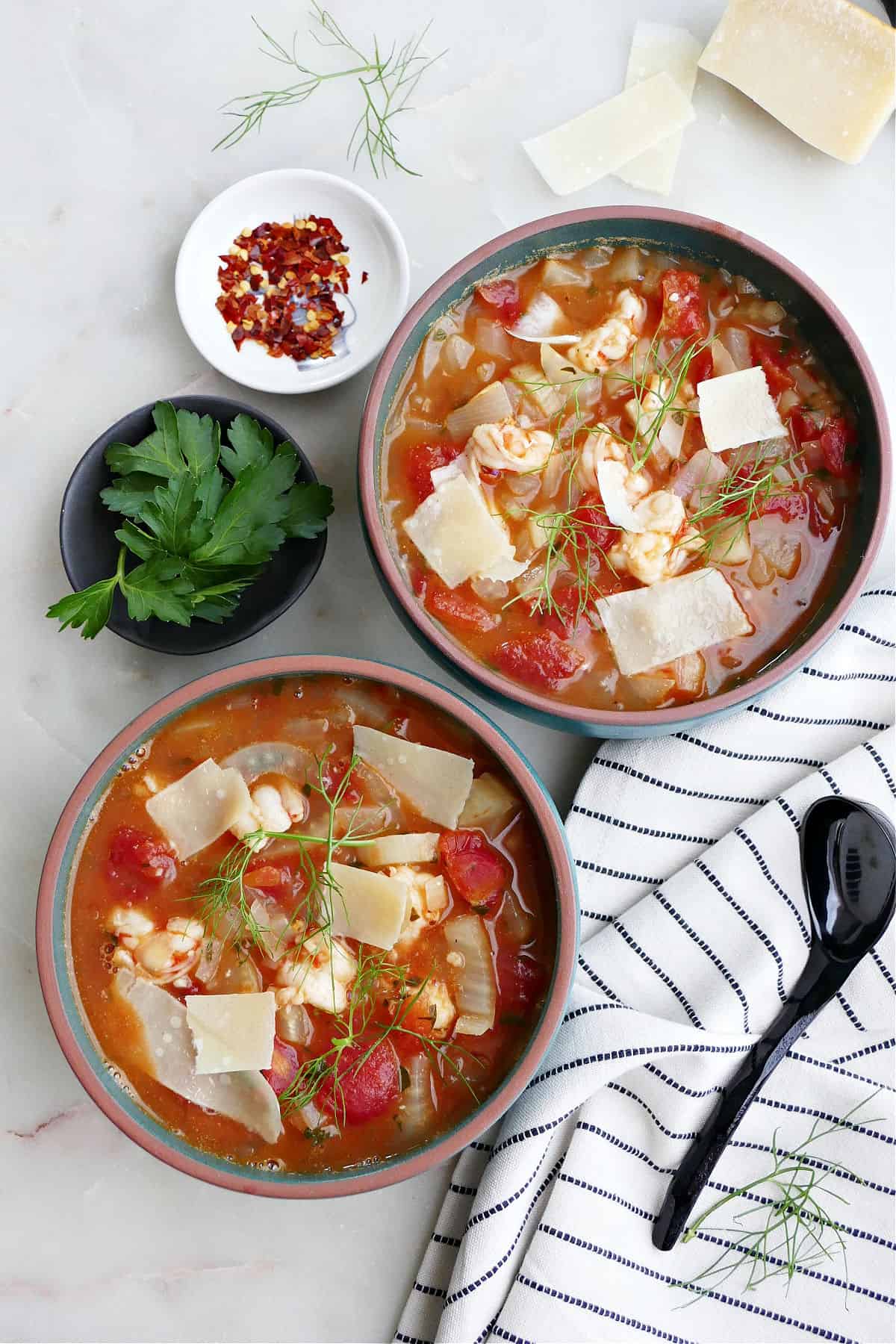 two bowls of fennel stew next to toppings and a napkin on a counter