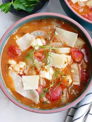 square image of bowl of fennel stew with shrimp in a soup bowl with toppings