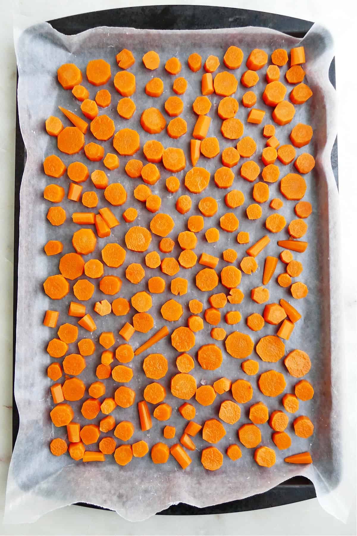 baking sheet lined with wax paper and frozen carrot medallions on a counter