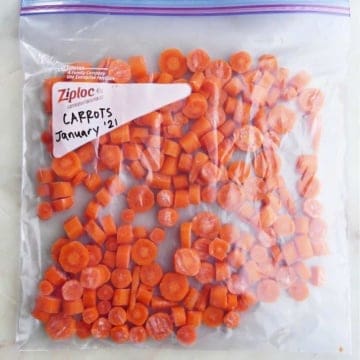 frozen carrot coins in a plastic bag labeled with the date on a counter