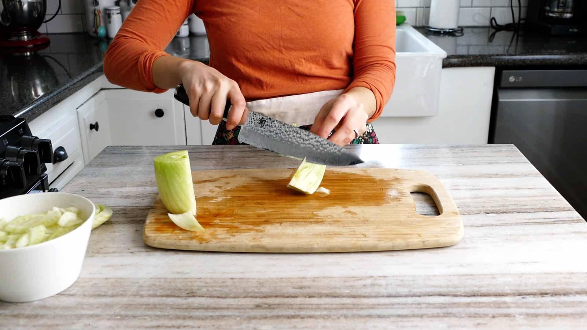 woman removing the core of a bulb of fennel using a chef's knife