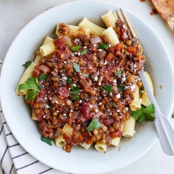 image of finished mushroom and lentil ragu in a serving dish with a fork next to striped napkin