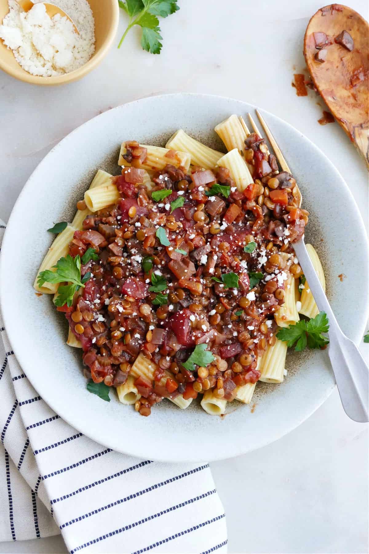 image of finished mushroom and lentil ragu in a serving dish with a fork next to striped napkin