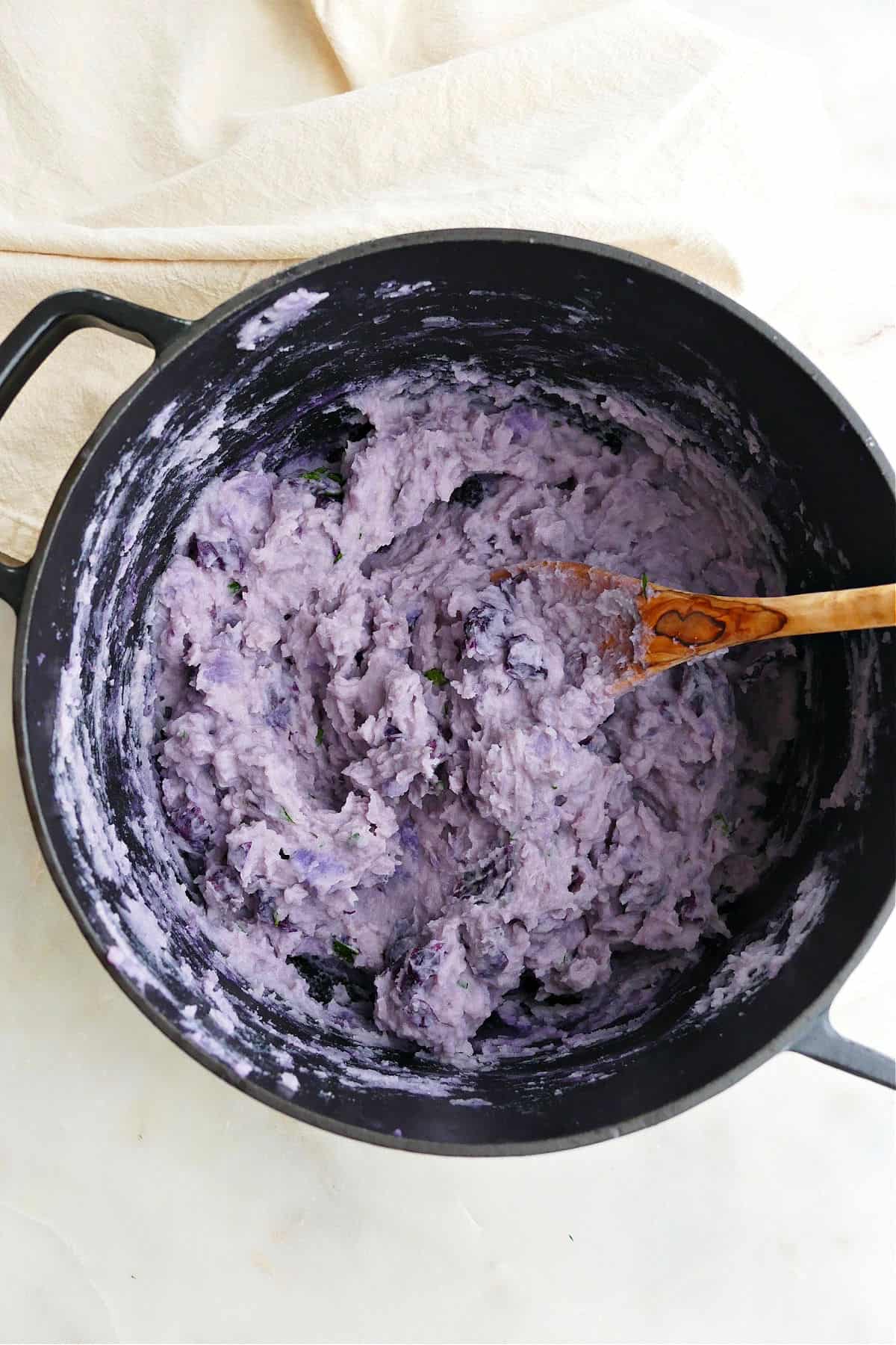 purple mashed potatoes in a pot with a wooden spoon on a counter