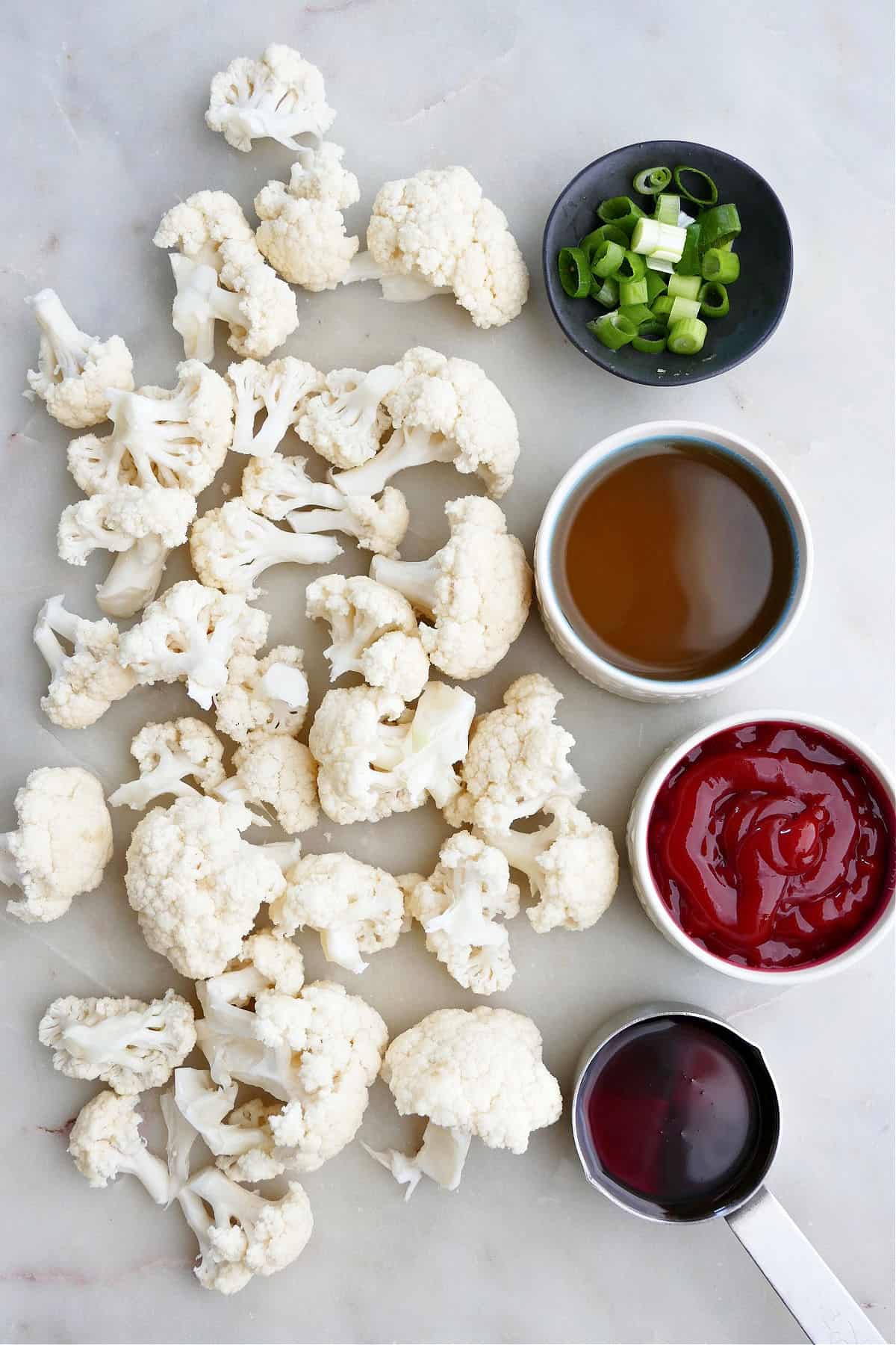 cauliflower florets next to ingredients for sweet and sour sauce spread out on a counter