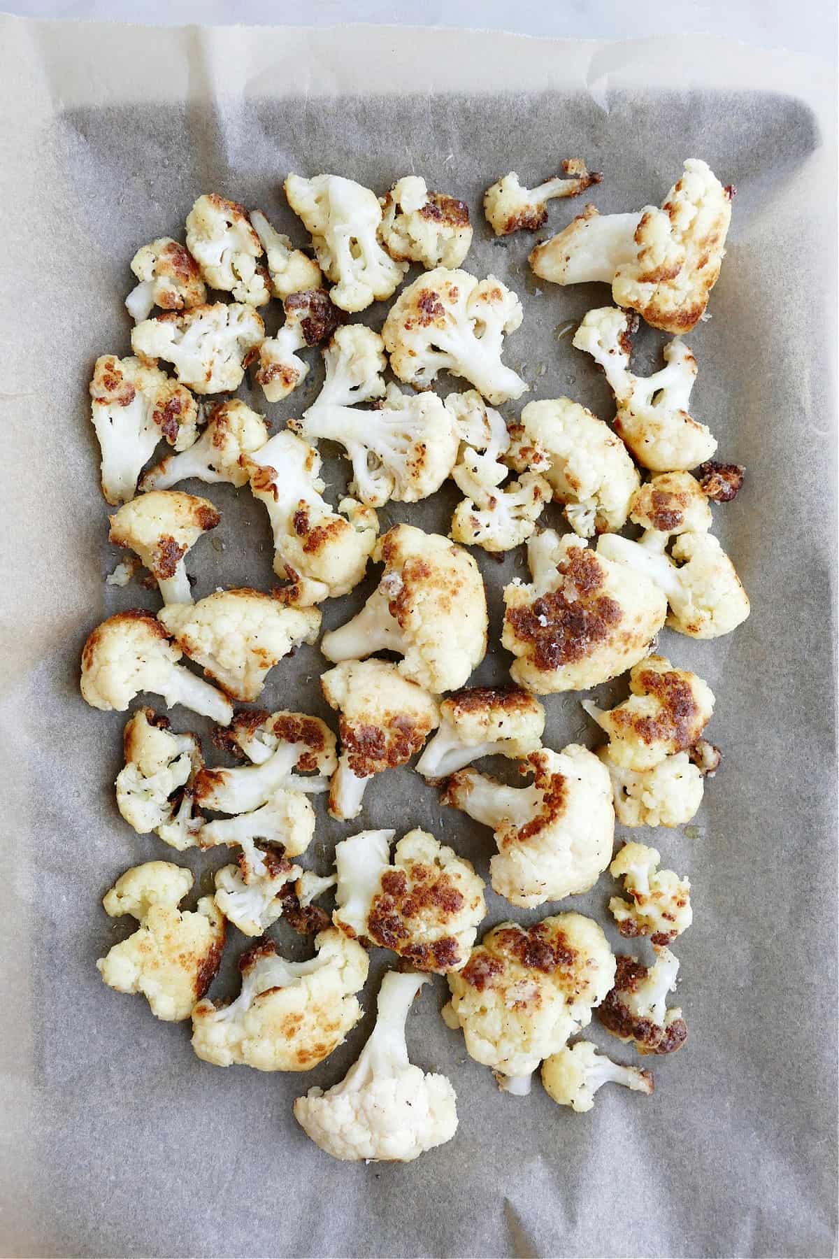 crispy cauliflower spread out on a baking sheet lined with parchment paper