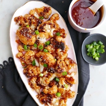 sweet and sour cauliflower on a serving dish on top of a napkin next to toppings