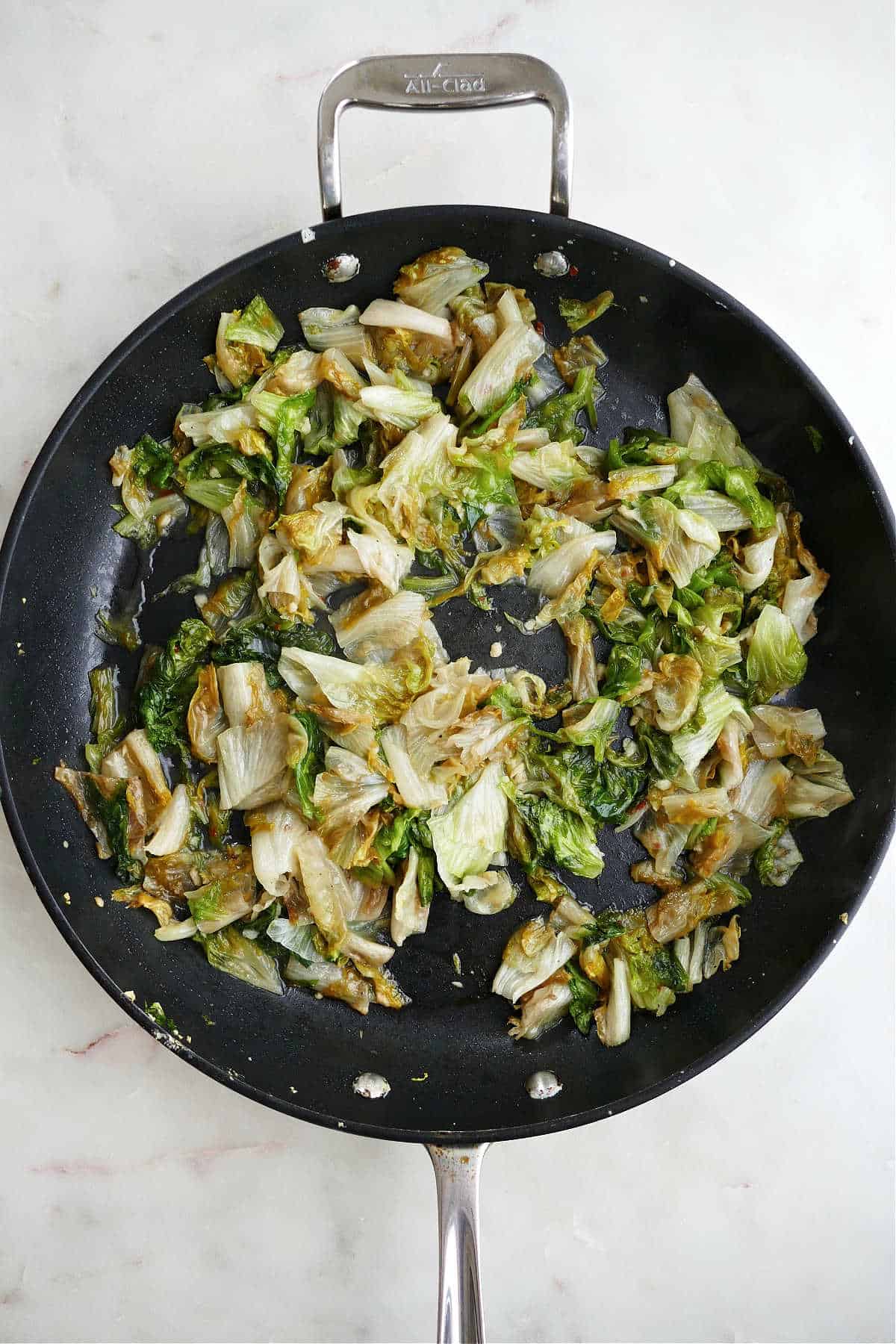 sauteed escarole cooking in a large black skillet on a white counter