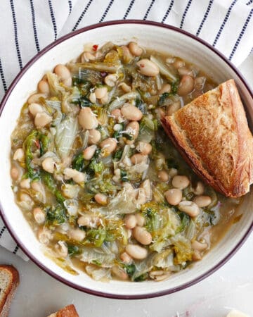 square image of a serving bowl with white beans and escarole and crunchy bread
