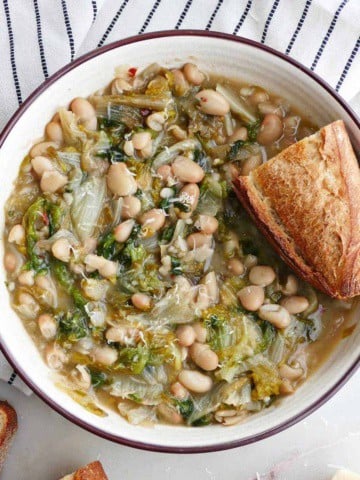 square image of a serving bowl with white beans and escarole and crunchy bread