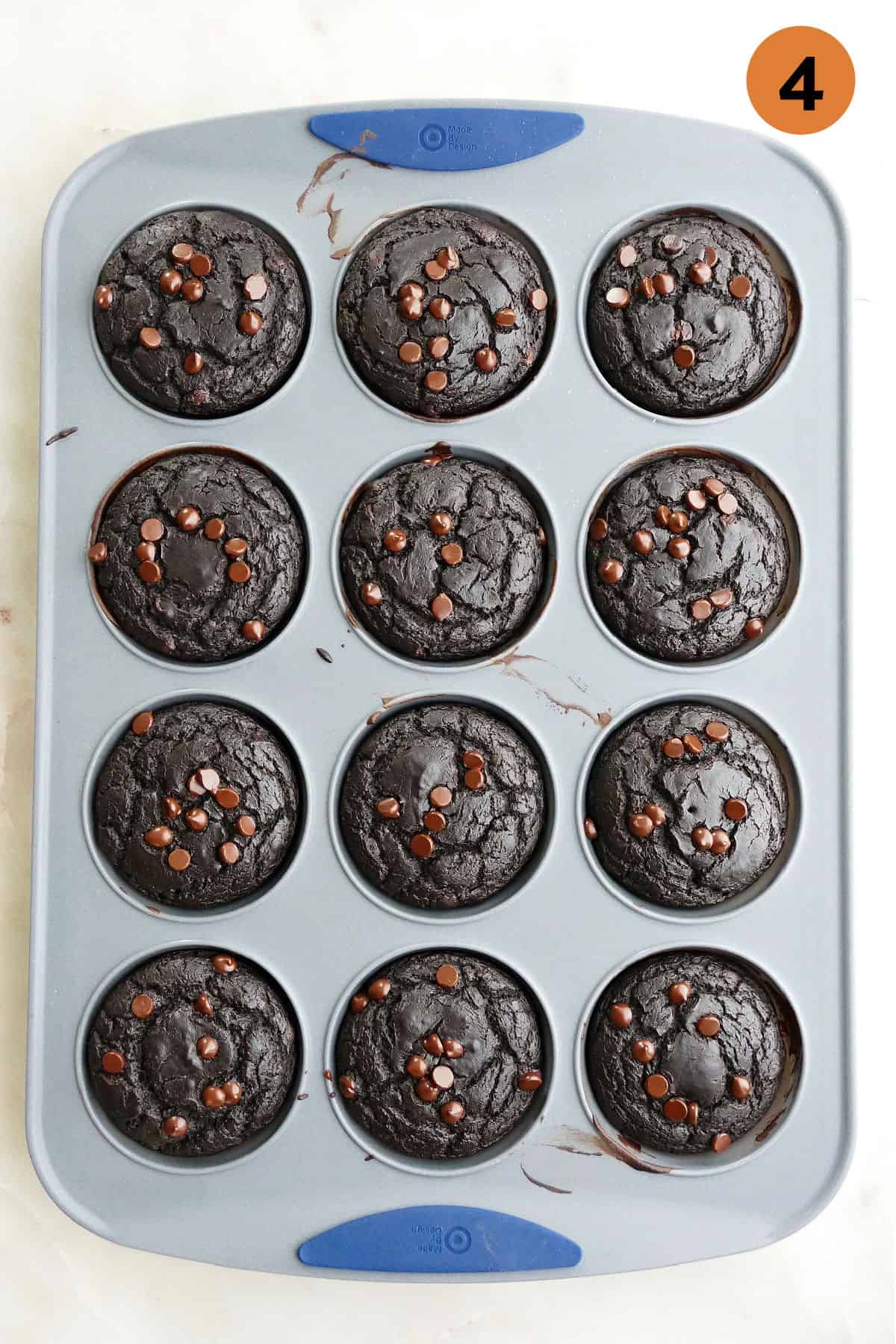 muffin pan with baked chocolate avocado muffins on a white counter