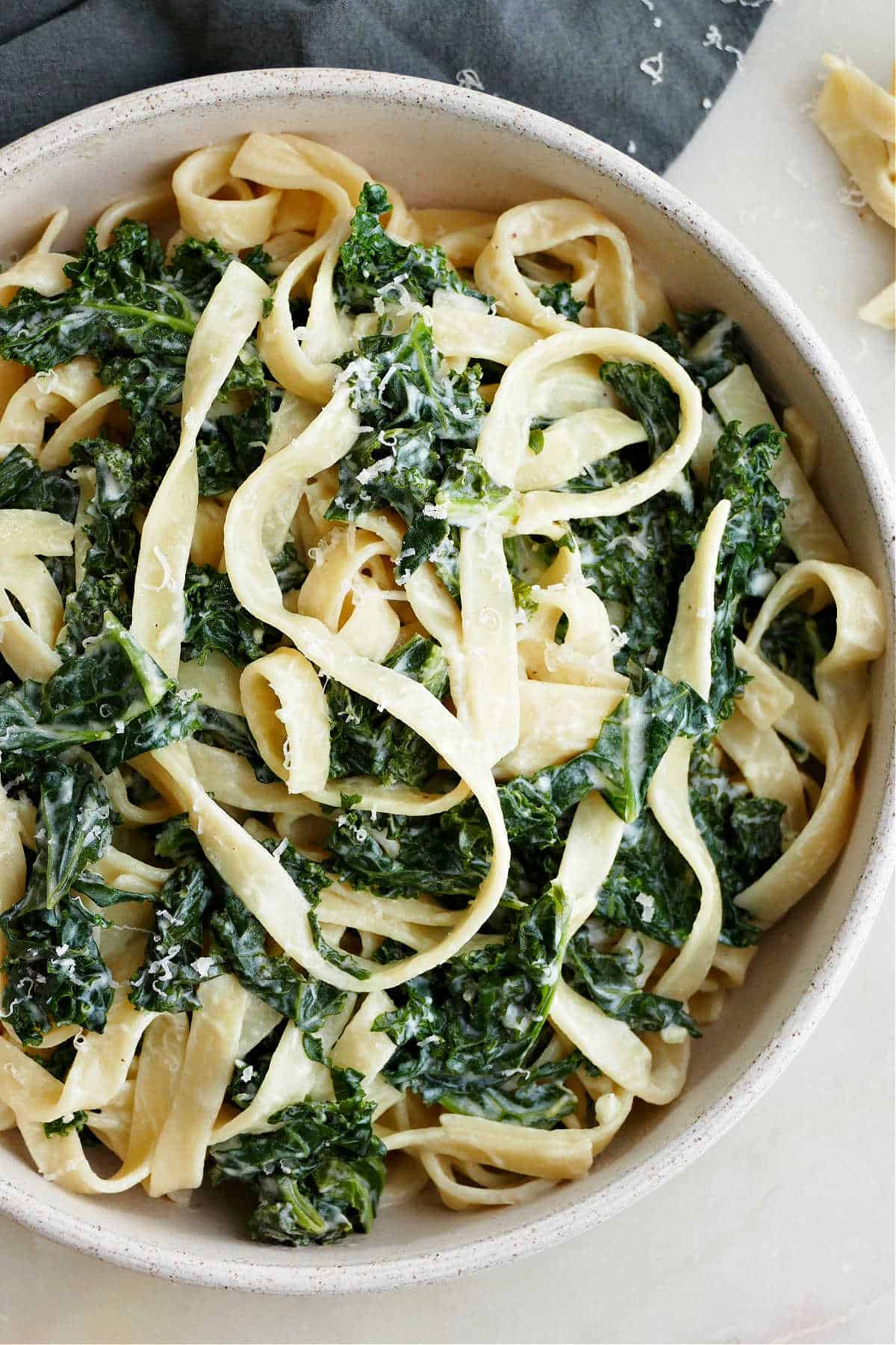 close image of kale over pasta noodles in a serving bowl on a counter