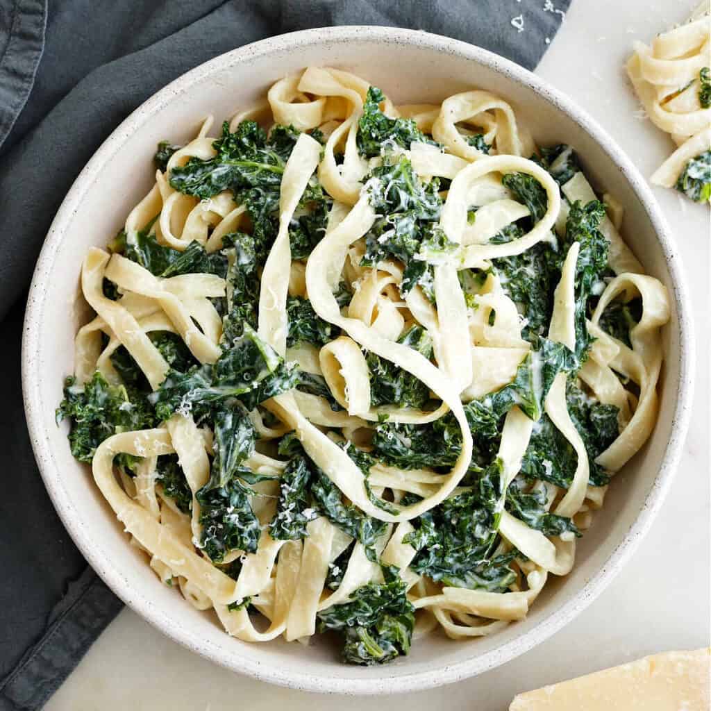 square image of creamy kale pasta in a serving bowl on a counter