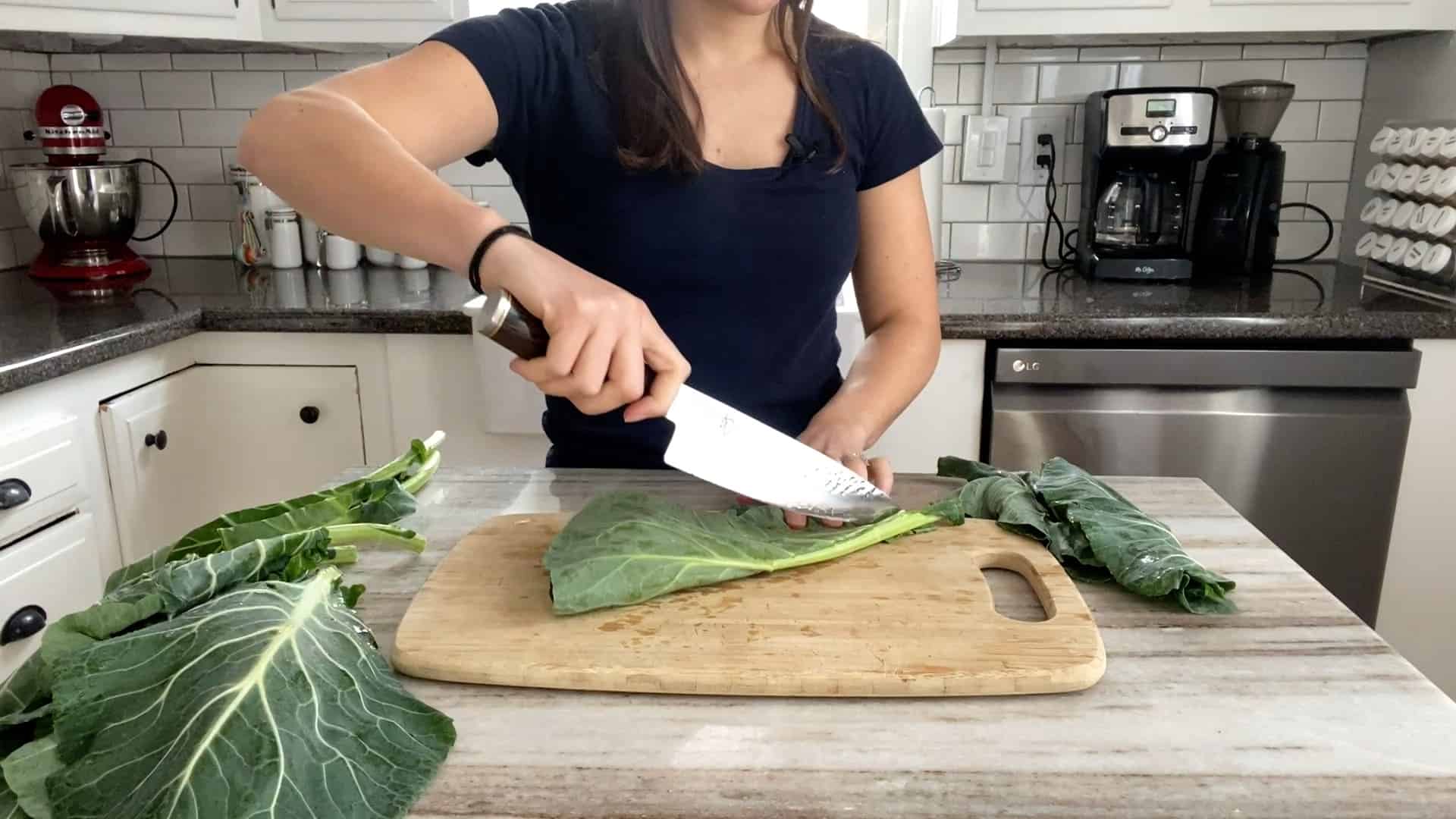woman slicing collard green leaves from their stems to cut into pieces