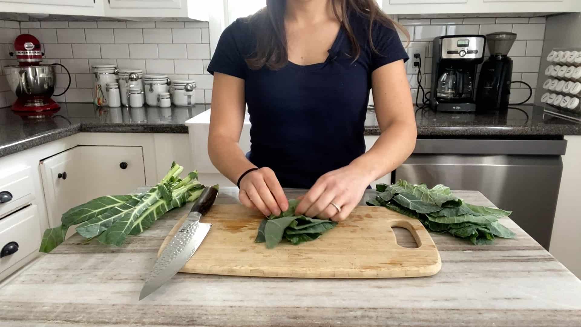 woman rolling collard green leaves into a bunch to cut into strip
