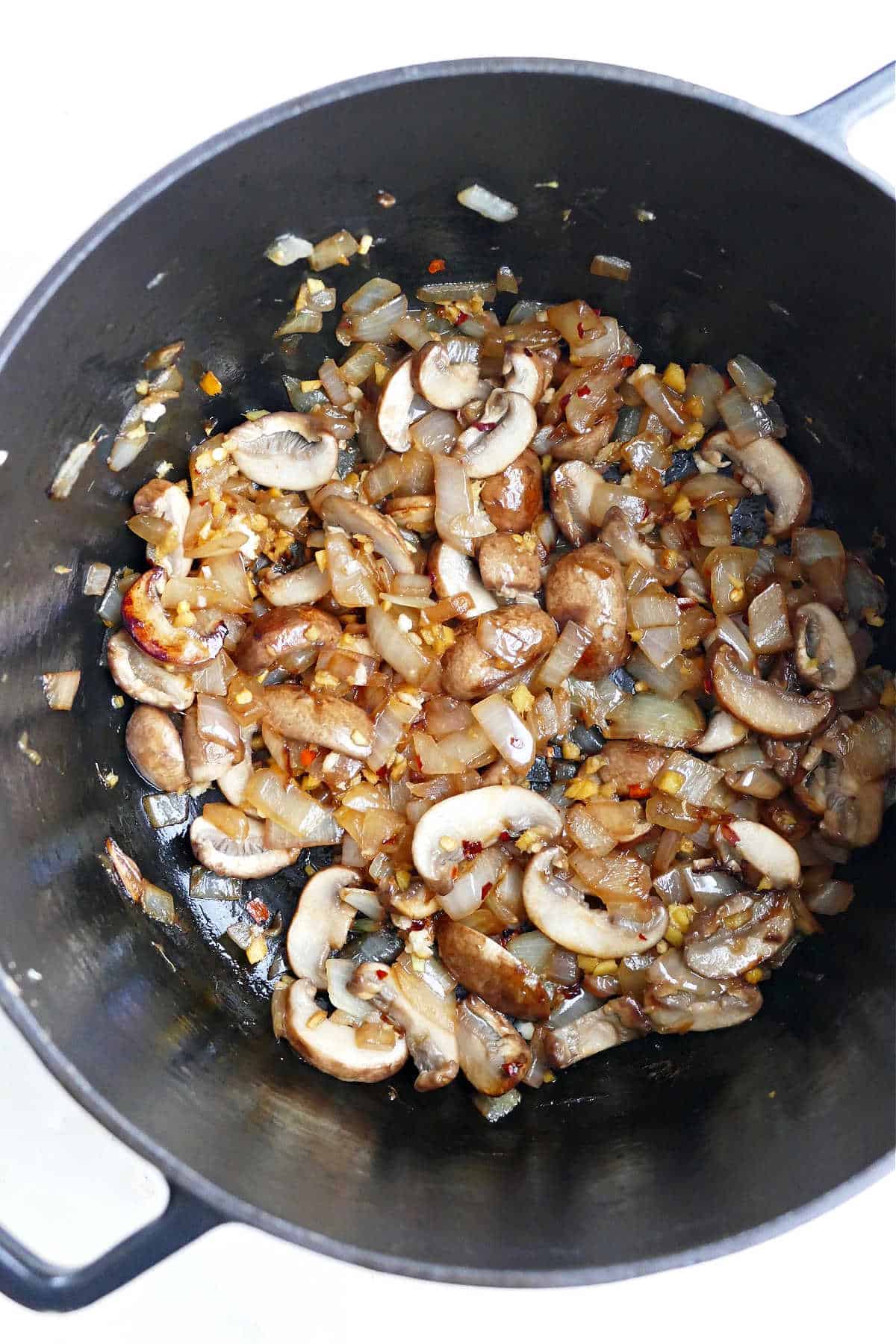 mushrooms, onion, and garlic cooking in olive oil in a large black pot
