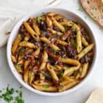 square image of caramelized shallot pasta in a serving bowl topped with chopped parsley