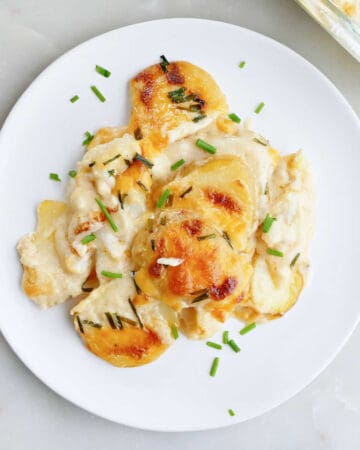 cheesy cauliflower and potatoes with chives on a plate on a counter