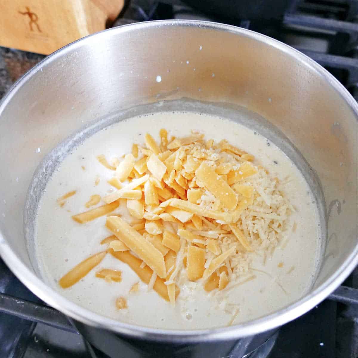 sauce with milk and shredded cheese cooking in a saucepan