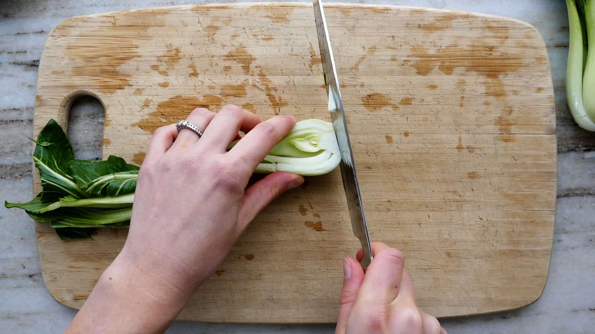 woman trimming the ends of bok choy on a cutting board