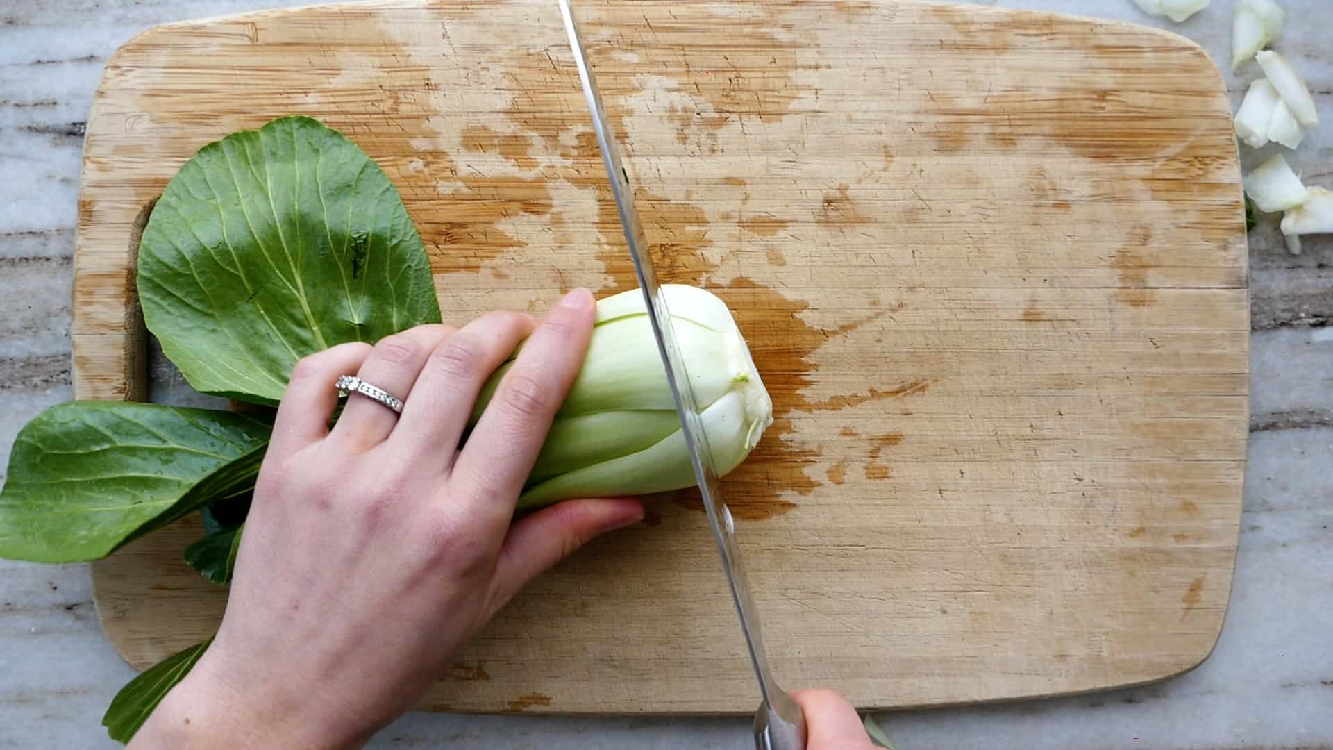 woman slicing off the root of bok choy on a cutting board