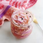 pickled shallots in a jar in front of a fork and towel