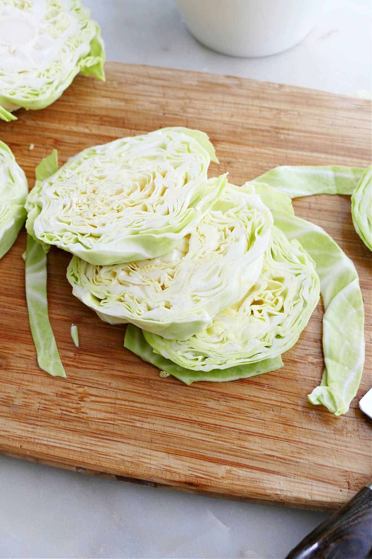 three sliced cabbage steaks on top of each other on a cutting board